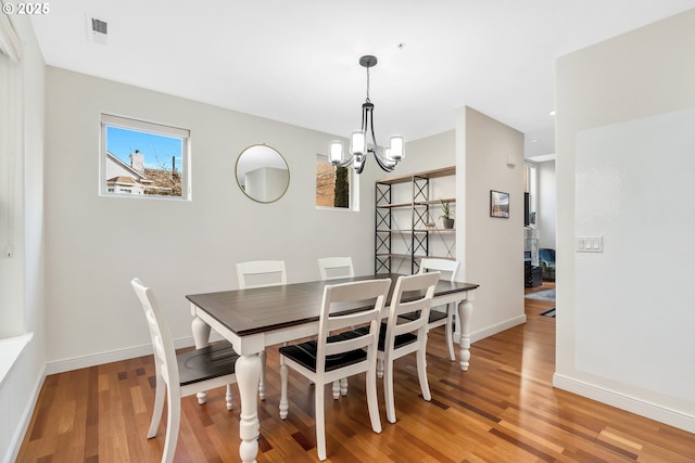 dining space featuring hardwood / wood-style flooring and an inviting chandelier