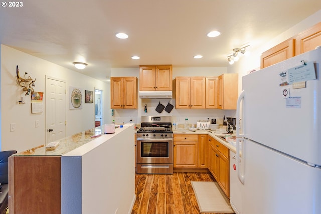 kitchen with light brown cabinetry, white refrigerator, light hardwood / wood-style flooring, and stainless steel range with gas cooktop