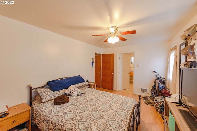 bedroom featuring light wood-type flooring, ensuite bath, and ceiling fan