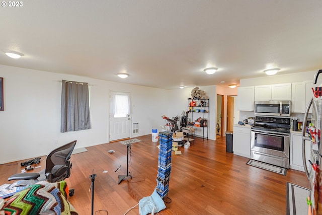 kitchen featuring hardwood / wood-style floors, stainless steel appliances, and white cabinets