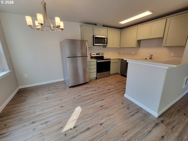 kitchen featuring appliances with stainless steel finishes, pendant lighting, light hardwood / wood-style flooring, sink, and a notable chandelier