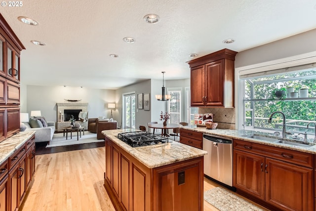 16675 SW Heceta Ct, Beaverton, OR 97007 - kitchen featuring dishwasher, a sink, black gas cooktop, a fireplace, and light wood-style floors