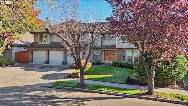 view of front of home featuring an attached garage, brick siding, concrete driveway, a tiled roof, and a front lawn