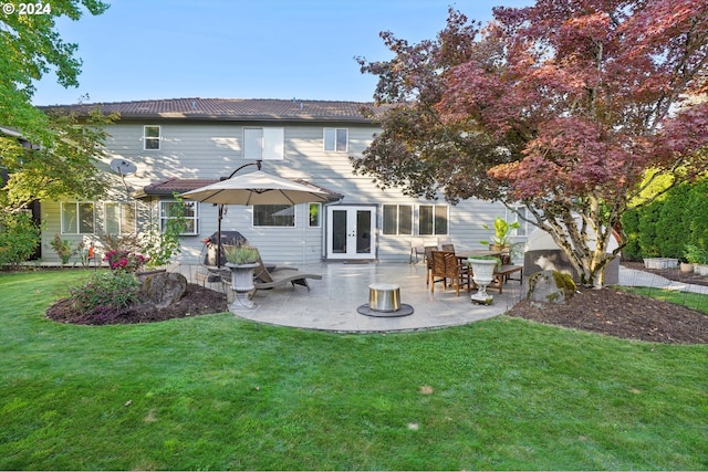 rear view of house with a patio, a fire pit, a yard, and french doors