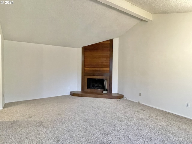 unfurnished living room with carpet flooring, a fireplace, vaulted ceiling with beams, and a textured ceiling