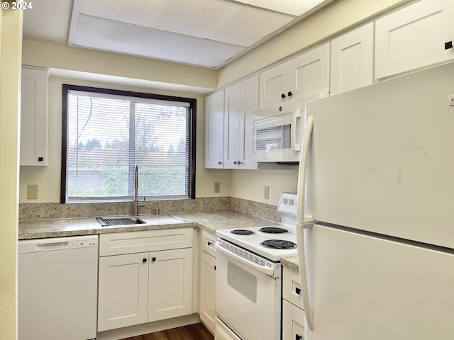 kitchen with dark wood finished floors, light countertops, white appliances, white cabinetry, and a sink