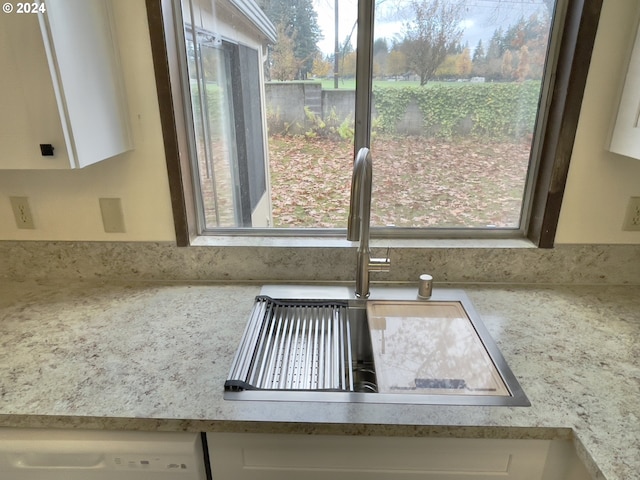 details with a sink, white cabinets, white dishwasher, and light countertops