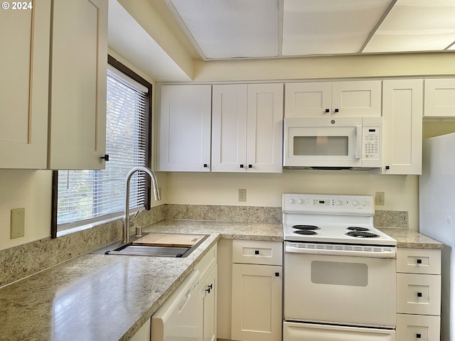 kitchen with a sink, white appliances, white cabinets, and light countertops