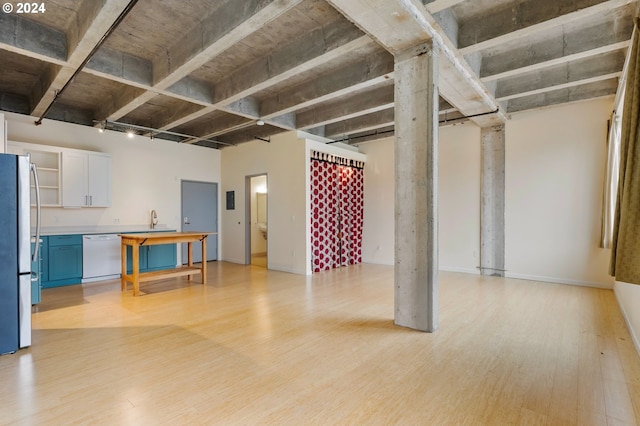 basement featuring stainless steel fridge and light hardwood / wood-style flooring