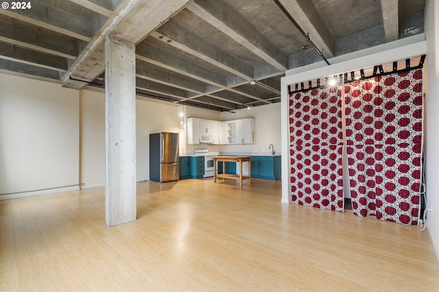 basement with stainless steel refrigerator, sink, and light hardwood / wood-style floors