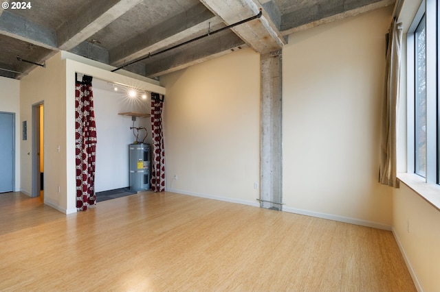 empty room featuring water heater, hardwood / wood-style floors, and plenty of natural light