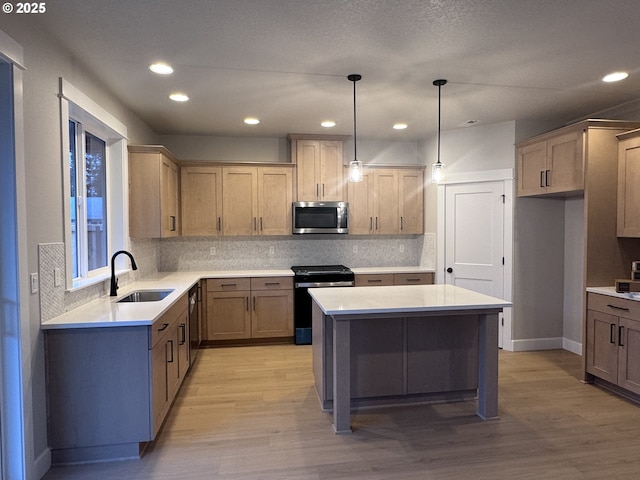 kitchen featuring a center island, hanging light fixtures, stainless steel appliances, light wood-type flooring, and sink