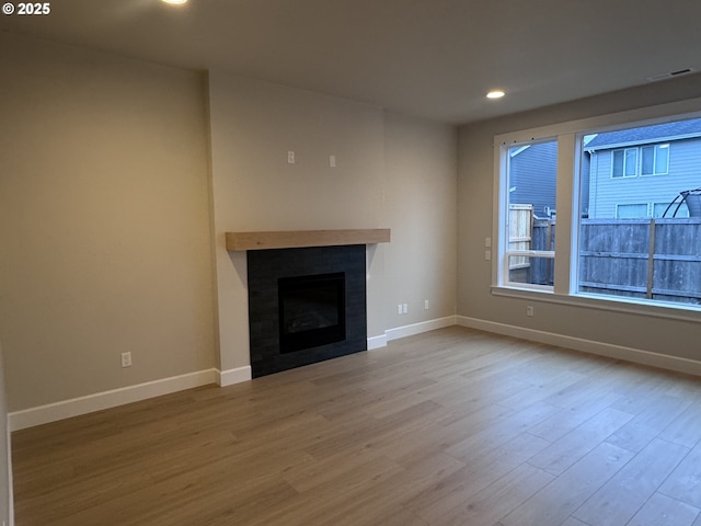 1006 NE 17th Ave, Canby, OR 97013 - unfurnished living room featuring wood finished floors, baseboards, recessed lighting, and a tiled fireplace