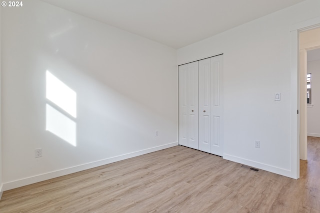 unfurnished bedroom with light wood-type flooring and a closet