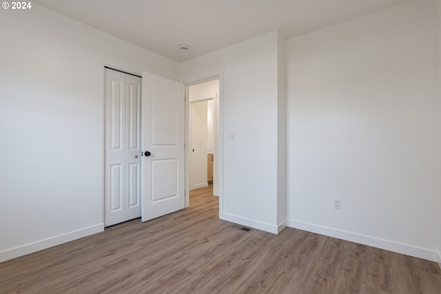 unfurnished bedroom featuring a closet and light wood-type flooring