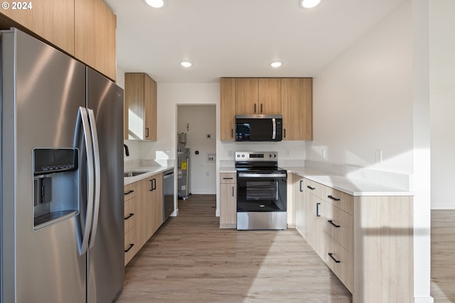 kitchen with light brown cabinetry, stainless steel appliances, light hardwood / wood-style flooring, and sink