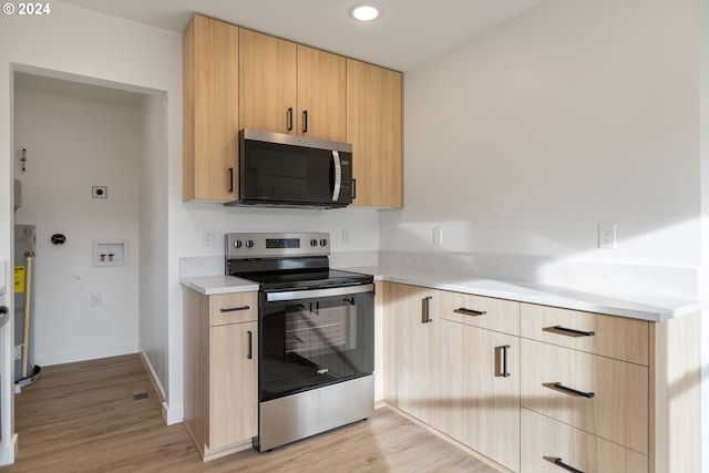 kitchen featuring water heater, light brown cabinets, light hardwood / wood-style floors, and appliances with stainless steel finishes