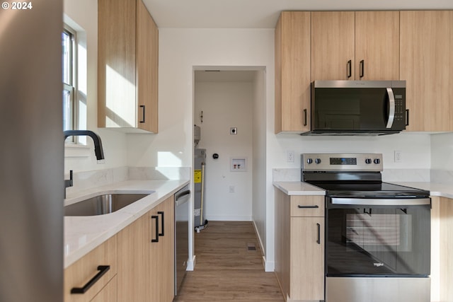 kitchen with light brown cabinets, light hardwood / wood-style floors, sink, and appliances with stainless steel finishes