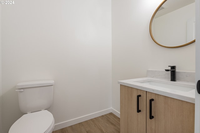 bathroom with toilet, vanity, and hardwood / wood-style flooring