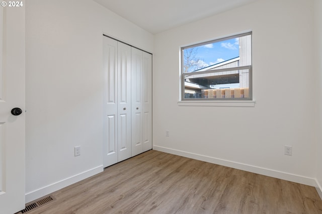 unfurnished bedroom with light hardwood / wood-style flooring and a closet