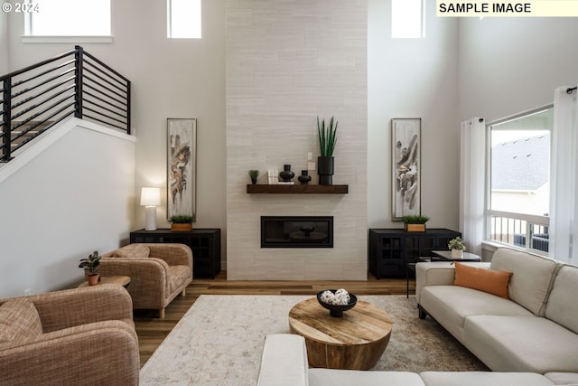 living room featuring dark hardwood / wood-style floors, a tiled fireplace, and a towering ceiling