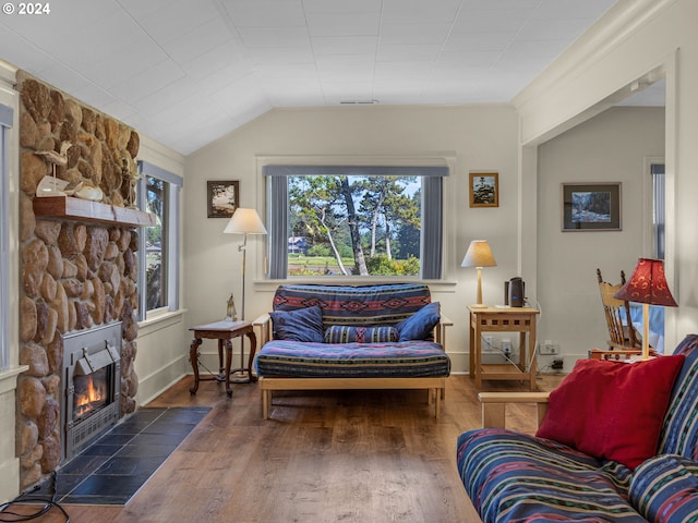 living room with lofted ceiling, a stone fireplace, and dark wood-type flooring