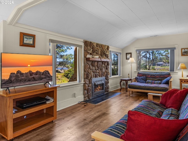 living room featuring a stone fireplace, a wealth of natural light, dark wood-type flooring, and lofted ceiling