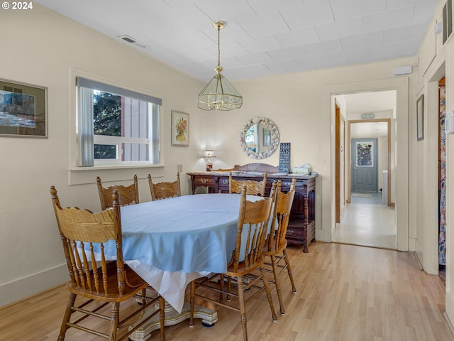 dining space with light hardwood / wood-style floors and a notable chandelier