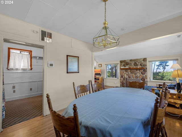 dining area with an inviting chandelier, a fireplace, and light hardwood / wood-style flooring