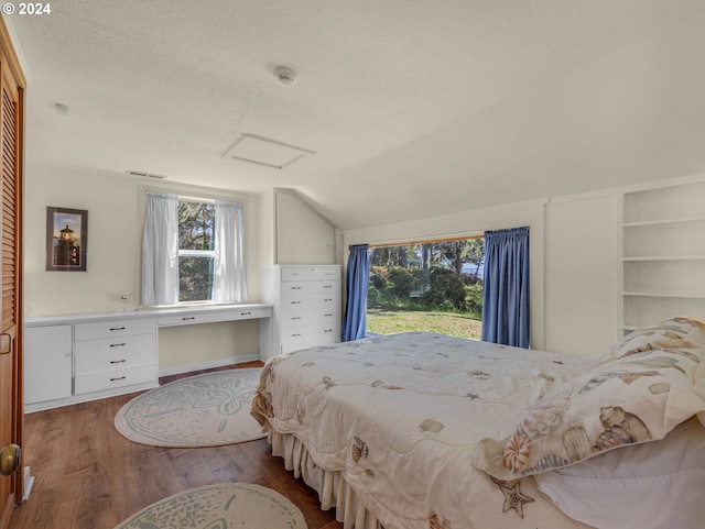 bedroom with a textured ceiling, multiple windows, vaulted ceiling, and hardwood / wood-style flooring