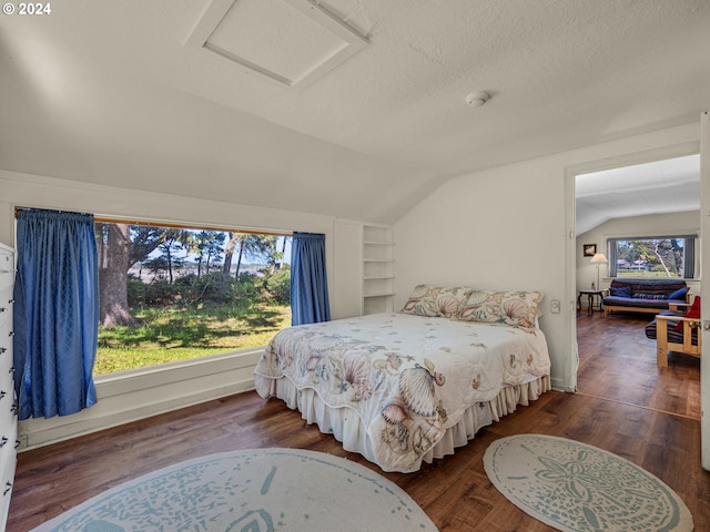 bedroom with a textured ceiling, lofted ceiling, dark wood-type flooring, and multiple windows