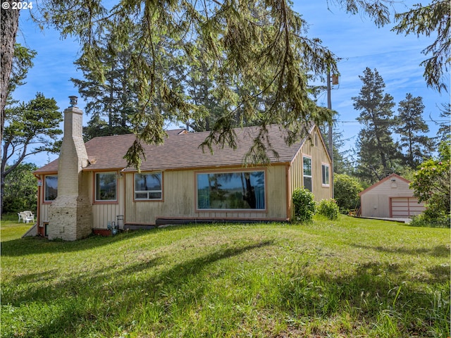 back of house with a storage unit and a lawn