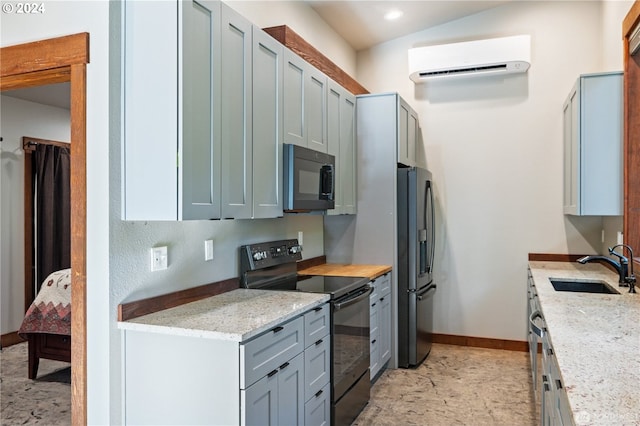 kitchen featuring light stone counters, black electric range oven, sink, stainless steel fridge, and an AC wall unit