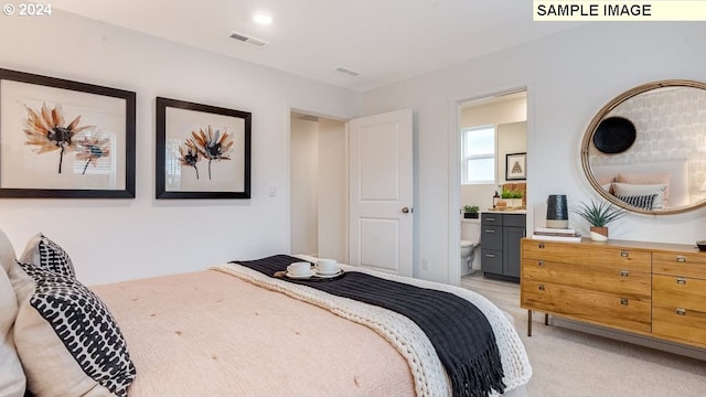 bedroom with light colored carpet and ensuite bath