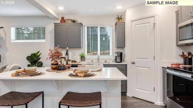 kitchen featuring gray cabinets, a kitchen bar, sink, and appliances with stainless steel finishes