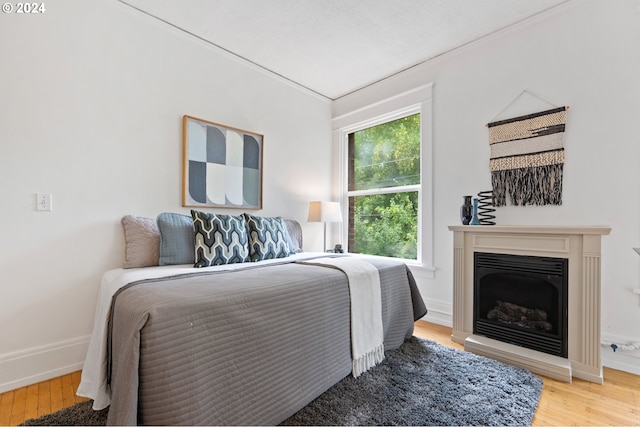 bedroom with baseboards, wood finished floors, and a fireplace