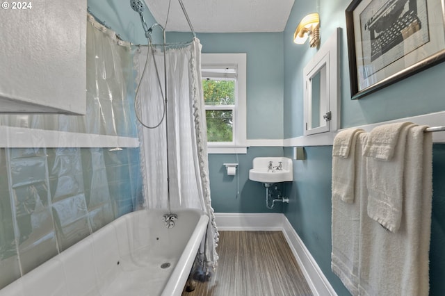 bathroom featuring shower / bathtub combination with curtain, baseboards, and a textured ceiling