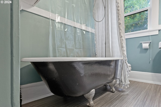 full bathroom featuring a freestanding bath, baseboards, and wood finished floors