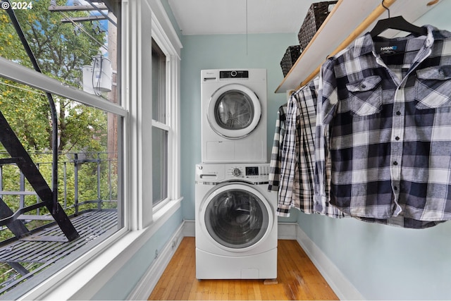 laundry area featuring laundry area, stacked washing maching and dryer, baseboards, and wood finished floors