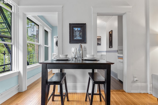 dining room with hardwood / wood-style floors, stacked washer and dryer, and baseboards