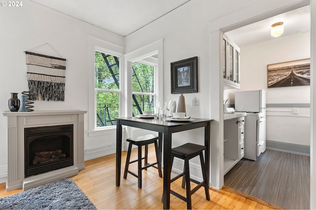 dining area featuring light wood-type flooring, baseboards, and a fireplace with raised hearth