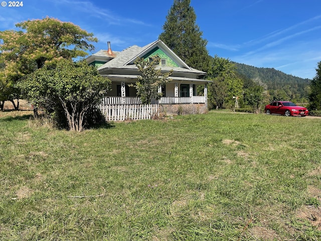 view of front of house with a mountain view, a front yard, and covered porch