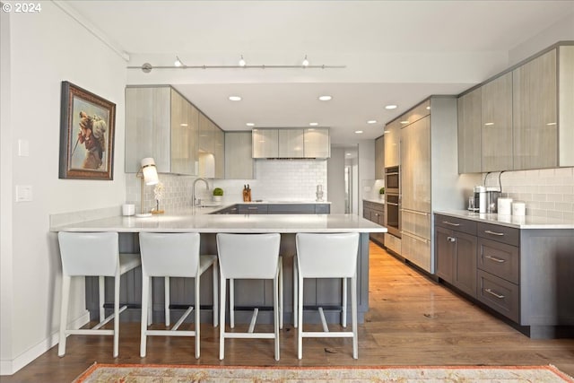 kitchen featuring tasteful backsplash, kitchen peninsula, and hardwood / wood-style floors