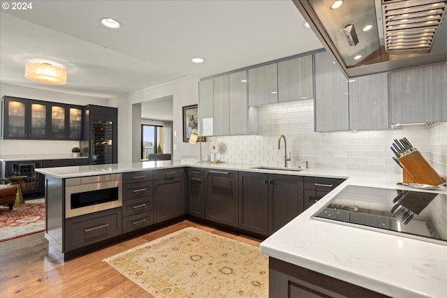 kitchen featuring black electric cooktop, light wood-type flooring, sink, tasteful backsplash, and kitchen peninsula