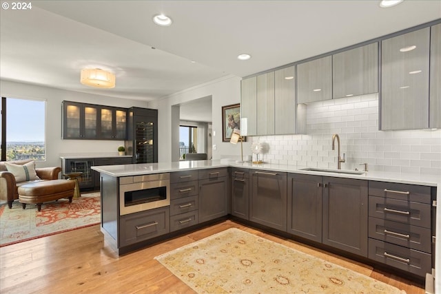 kitchen featuring backsplash, kitchen peninsula, a healthy amount of sunlight, and light hardwood / wood-style floors