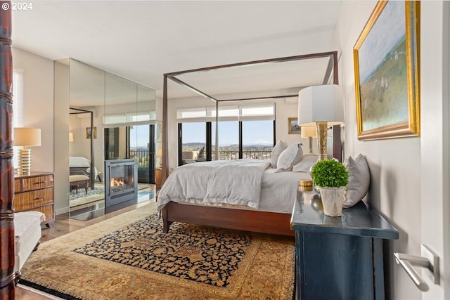 bedroom featuring a multi sided fireplace and hardwood / wood-style floors