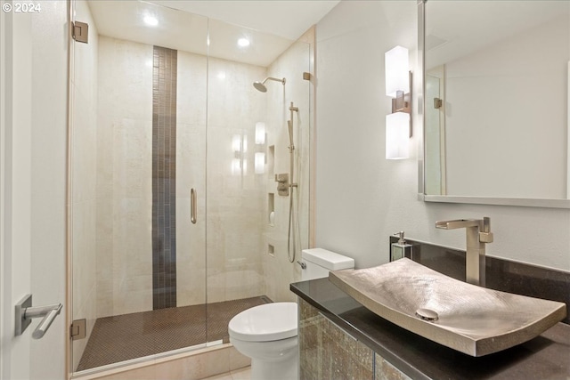 bathroom with a shower with shower door, vanity, and toilet