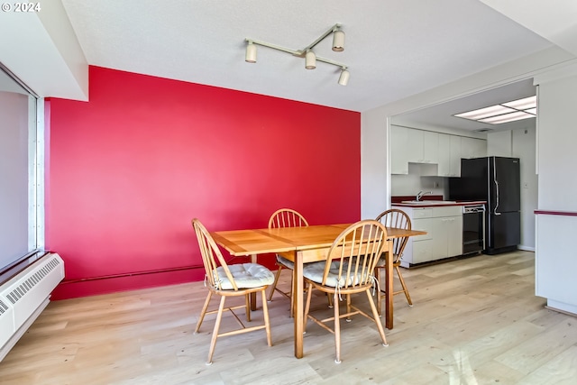 dining room with light hardwood / wood-style flooring, baseboard heating, and sink