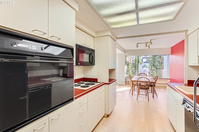 kitchen featuring light wood-type flooring, sink, dishwasher, white cabinets, and white electric stovetop