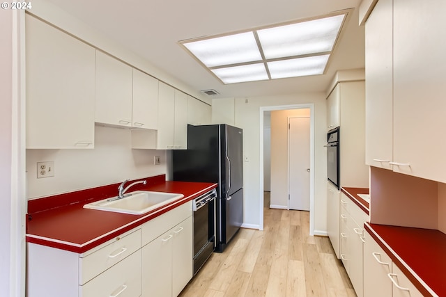 2323 SW Park Pl Unit 302, Portland, OR 97205 - kitchen with a sink, black appliances, light wood-style flooring, white cabinets, and dark countertops